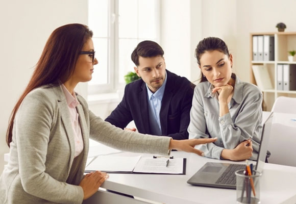 Couple sitting with a female insurance broker showing a project on a laptop screen