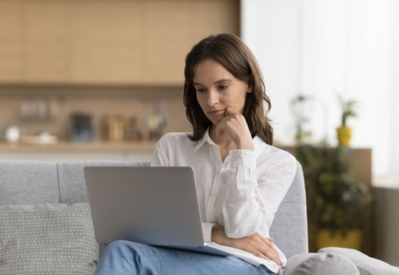 A girl is thinking and looking at a laptop