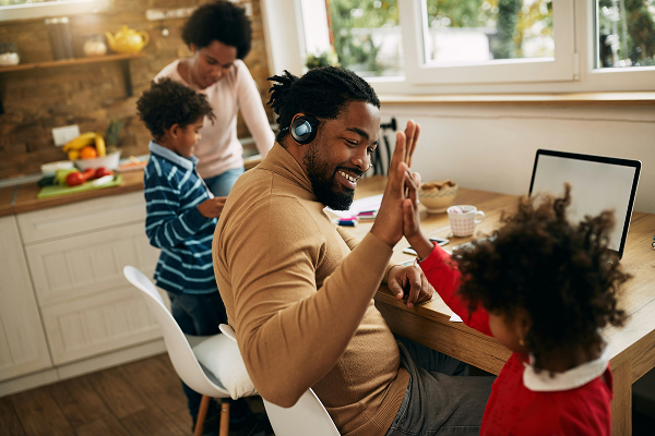 Father working from home high-fiving daughter in kitchen