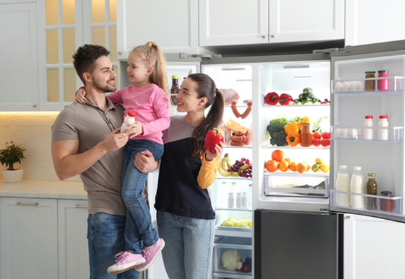 Family with child standing by open fridge freezer