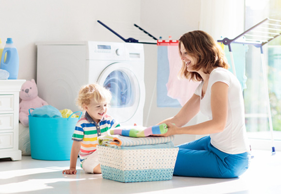 mother and child folding laundry near washing machine – Washing Machine Insurance