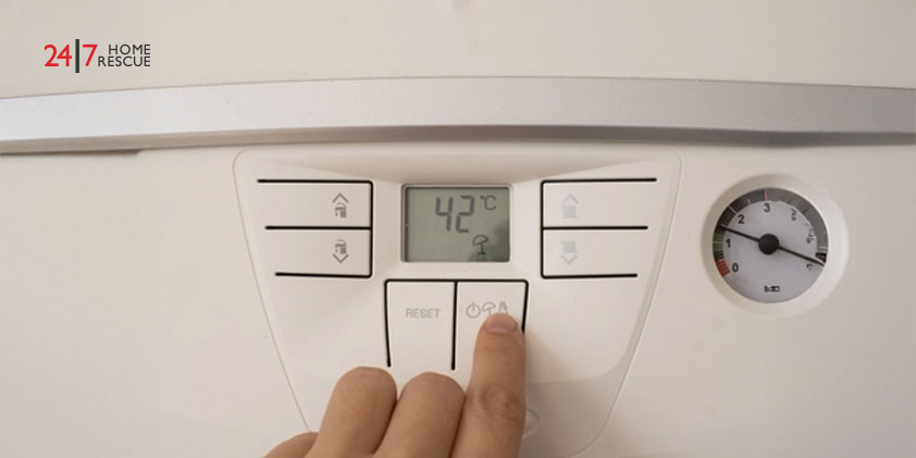 A person is hand adjusting the temperature on a boiler dial for energy efficiency.