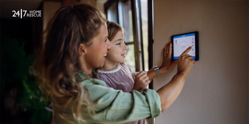 Mother and daughter lowering temperature on a smart thermostat for energy efficiency