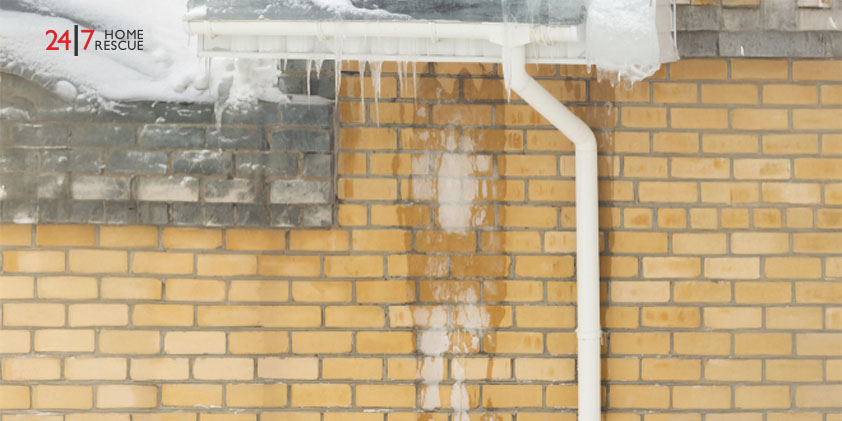 Ice-covered brick wall with frozen downpipe