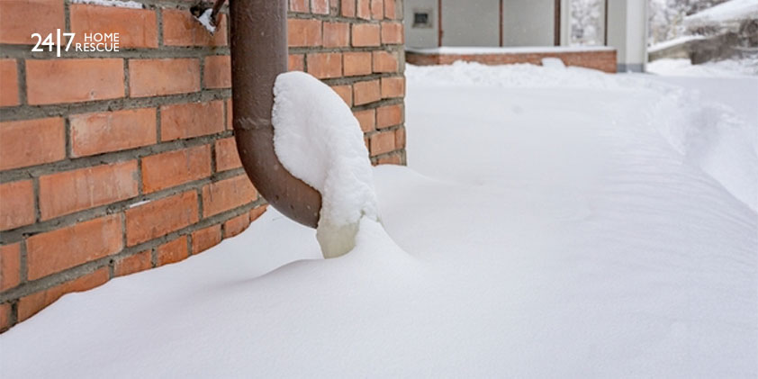 Frozen outdoor pipe on the brick exterior wall.