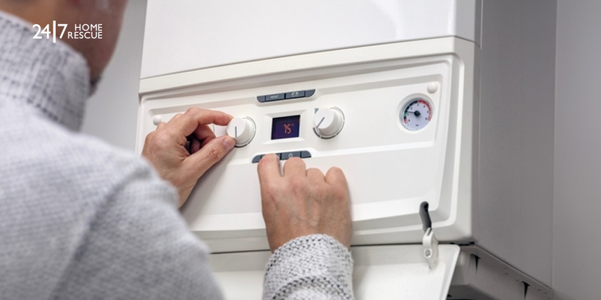 A person adjusting the thermostat on their central heating system 