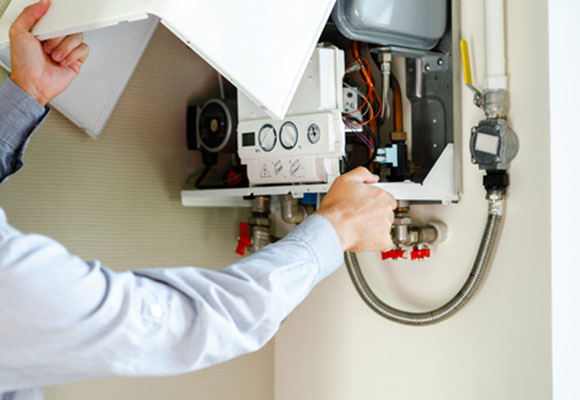 Engineer opening a boiler casing to inspect internal components and pipework