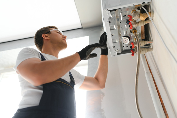Engineer wearing safety goggles and gloves servicing an open boiler unit