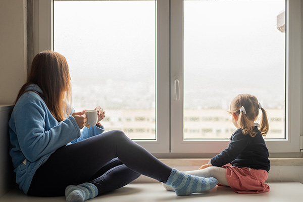Mother and daughter sitting by window