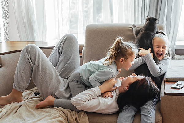 Mom and daughters laughing on sofa
